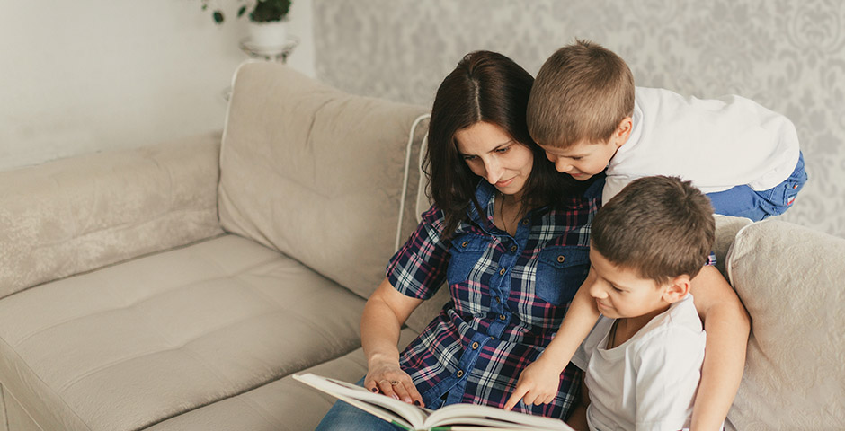 Madre leyendo con sus hijos, representando el beneficio de pensión por hijo a cargo.