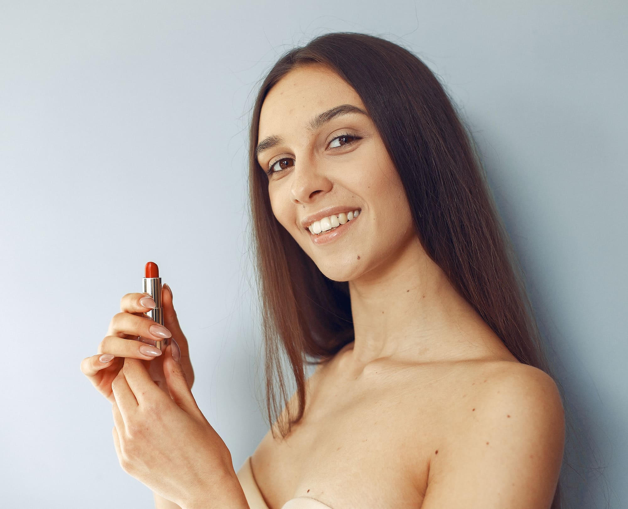 Mujer sonriente con pintalabios rojo, representando la teoría del pintalabios y su impacto económico. 