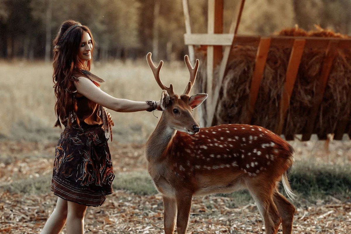 Mujer acariciando un ciervo en la naturaleza, simbolizando la conexión y prevención de la pérdida de biodiversidad.