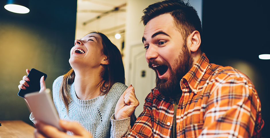 Pareja emocionada mirando un móvil, celebrando qué hacer tras ganar la lotería.