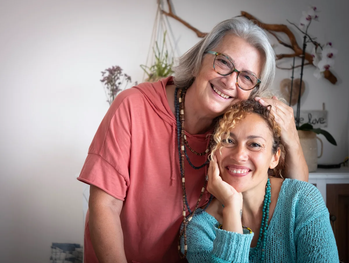 Mare i filla abraçant-se i somrient en un entorn càlid, con alzheimer hereditari.