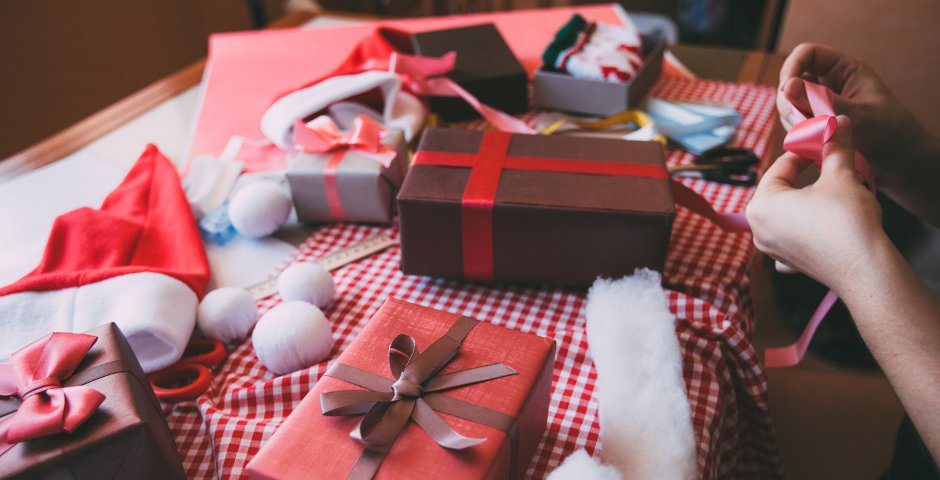 Mesa llena de regalos envueltos y materiales, ideal para ahorrar en regalos esta Navidad.