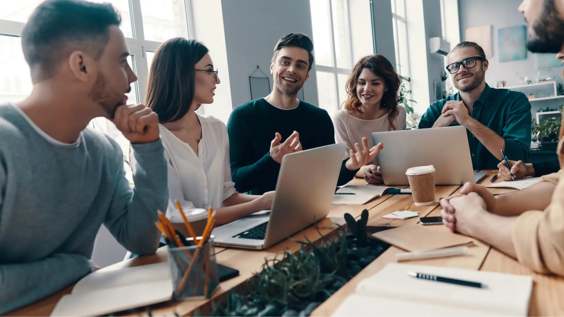 Un grup de joves professionals discutint idees en una reunió de treball col·laborativa.
