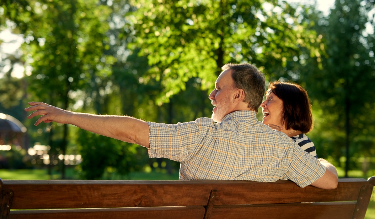 Pareja de jubilados sonrientes en un parque, simbolizando la revalorización de las pensiones.