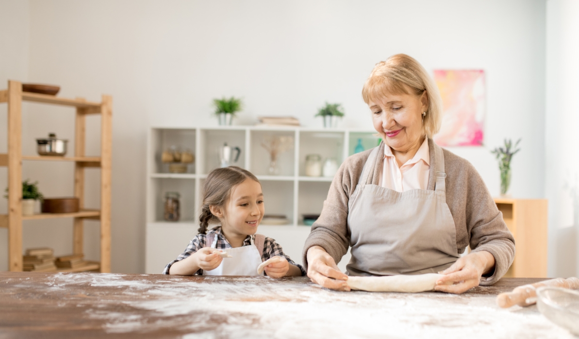 Abuela cocinando con su nieta, fomentando la salud mental en mayores con actividades familiares.