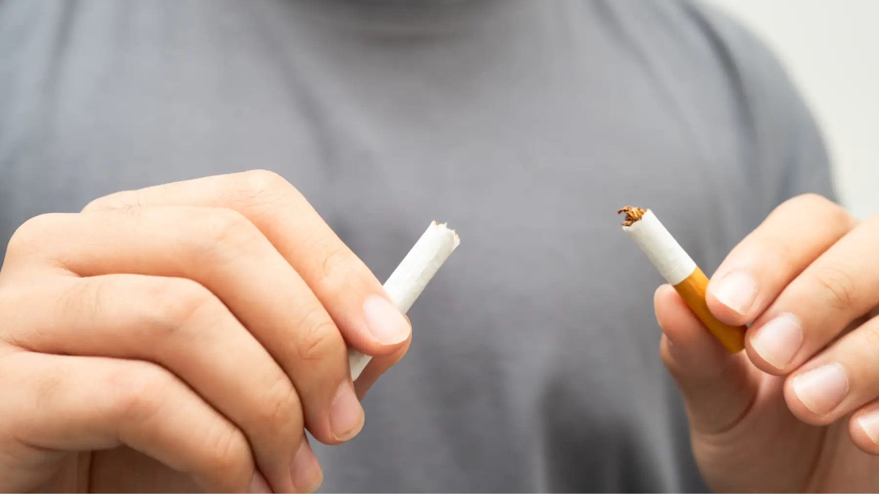 Manos rompiendo un cigarrillo, representando hábitos que pueden encarecer un seguro de vida.