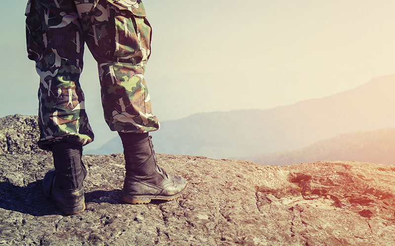Soldado en uniforme de camuflaje de pie sobre una roca, representando el servicio militar y jubilación.