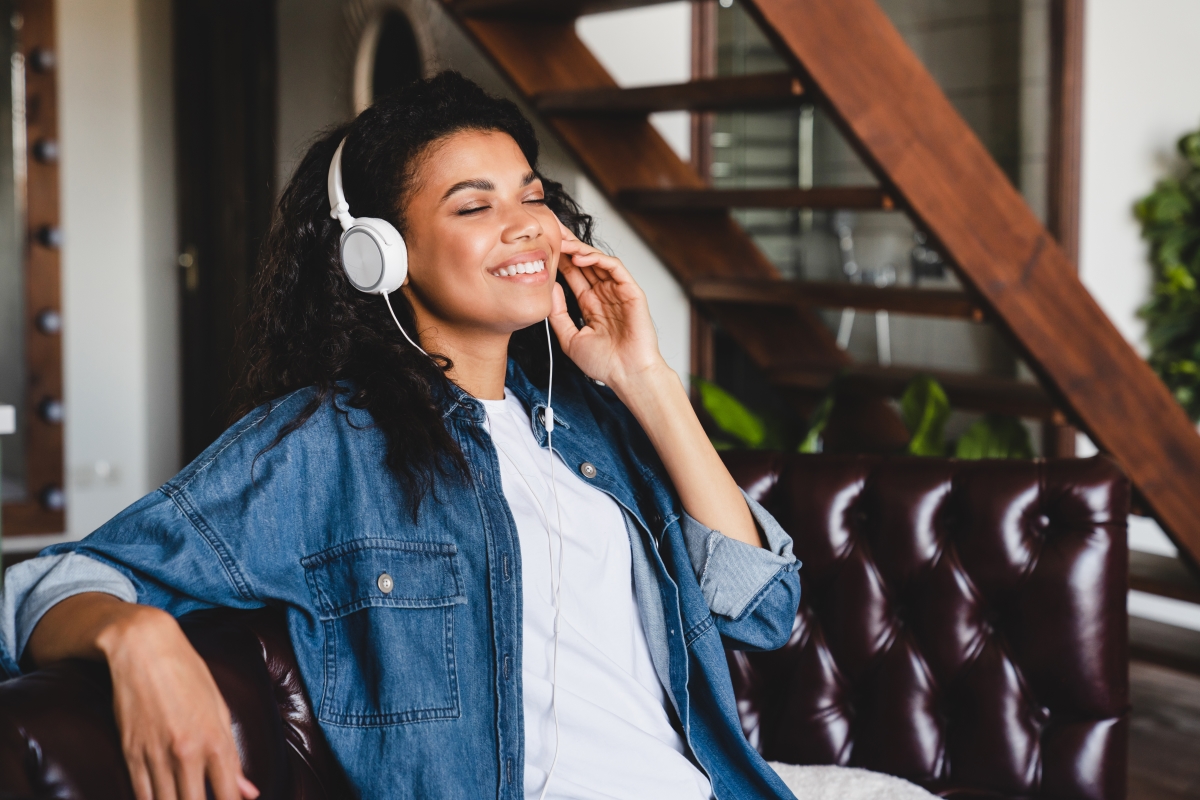 Joven escuchando música con auriculares, disfrutando del bono cultural en casa.
