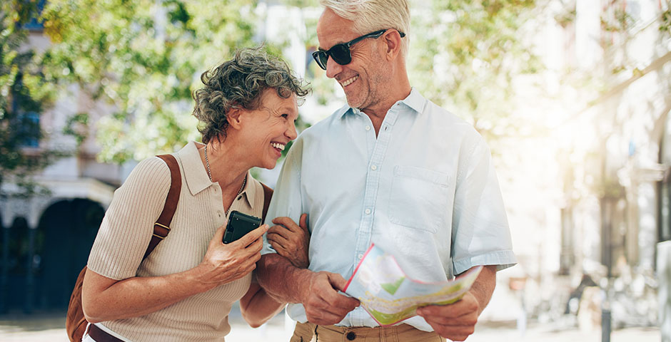 Una pareja mayor sonriente disfruta planificando su jubilación anticipada al aire libre.