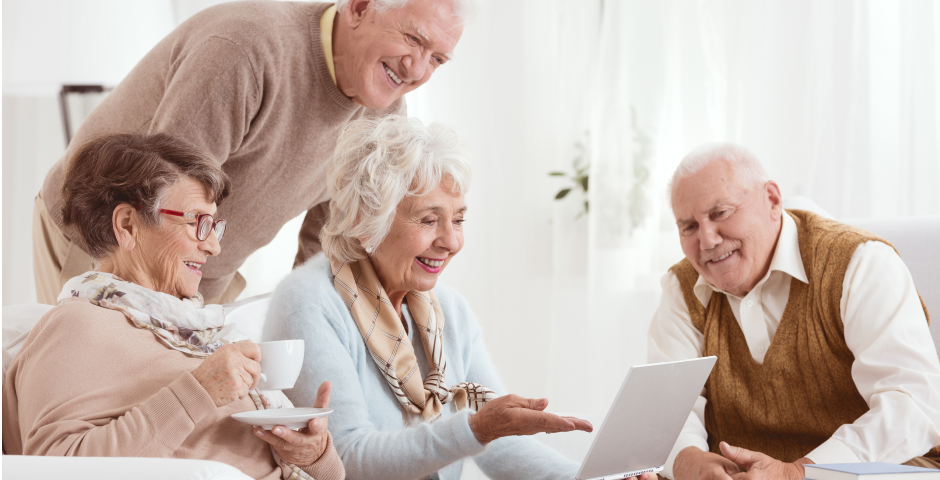 Grupo de jubilados sonrientes usando un ordenador, representando beneficios de la tarjeta pensionista.