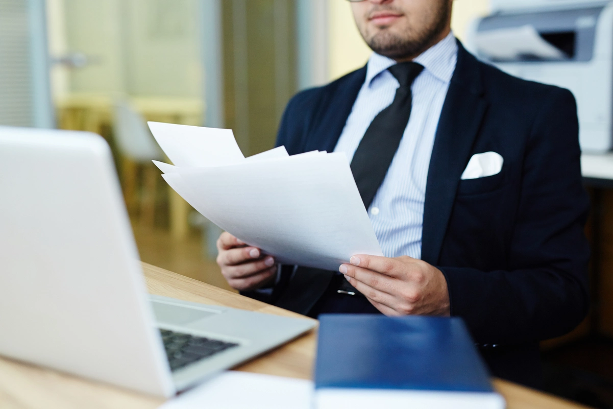 Hombre con traje revisando documentos en oficina, representando el proceso de elaboración de un testamento vital.