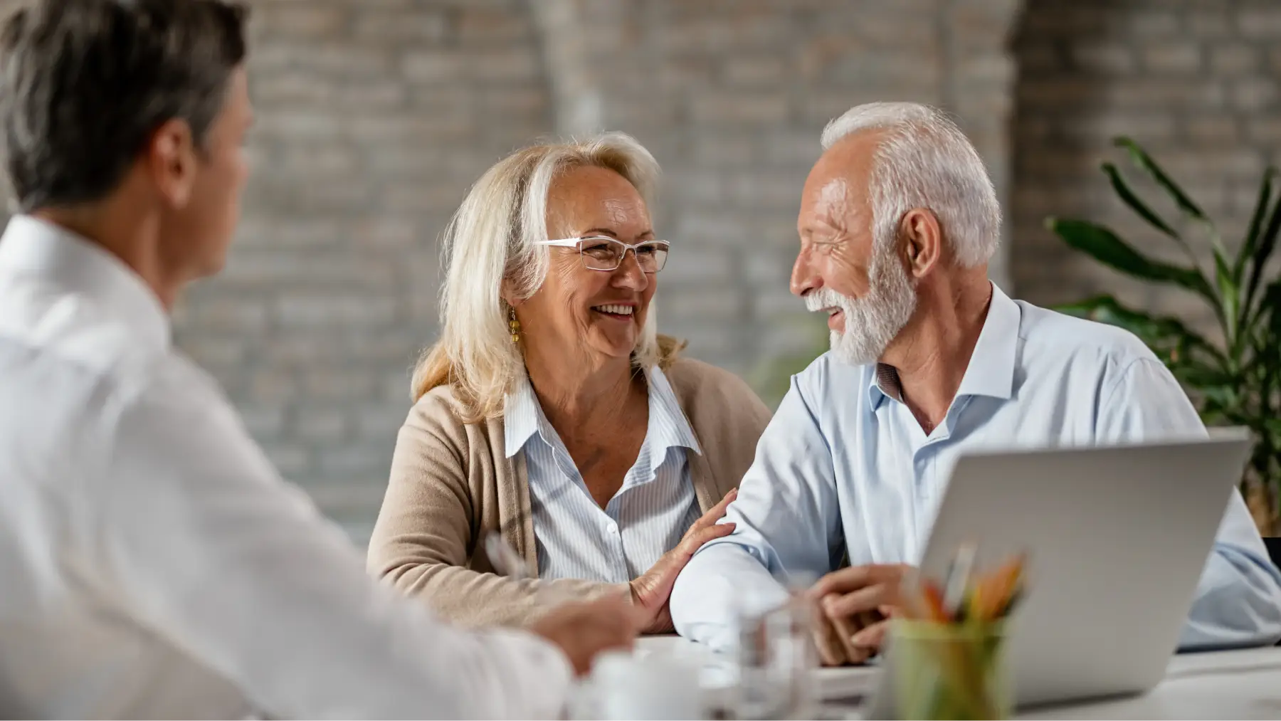 Pareja sonriente recibiendo asesoramiento sobre diferentes tipos de planes de pensiones.
