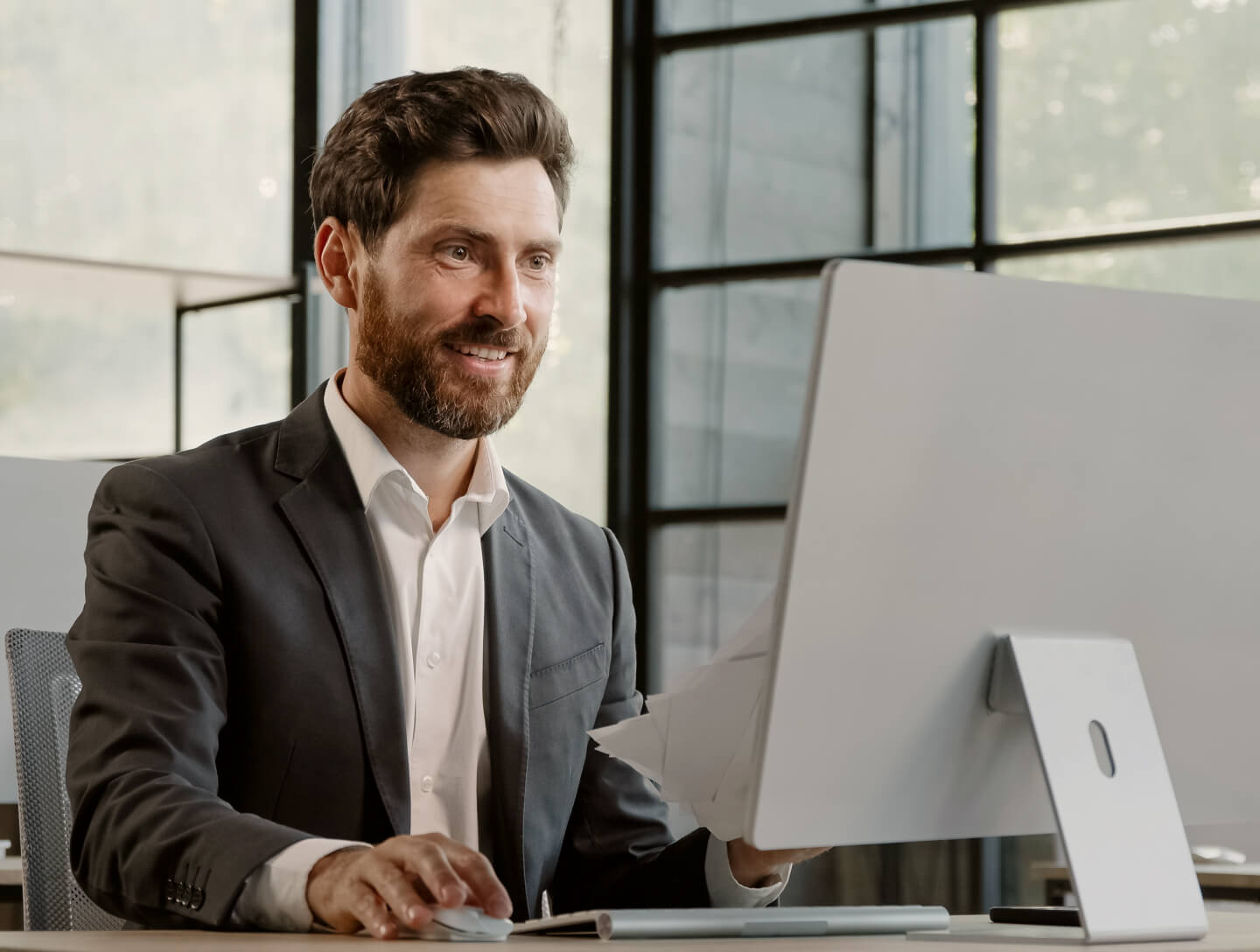 Professional at office computer, associated with GeroCaixa pension plans.