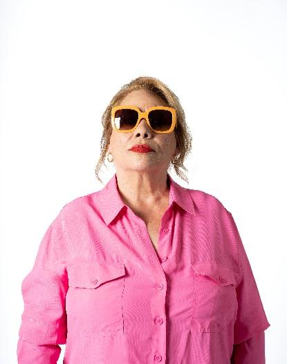 Dona amb ulleres de sol i camisa folgada posant amb actitud segura.