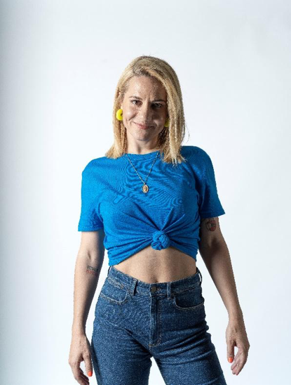 Dona amb samarreta nuada i texans posant amb expressió confiada.