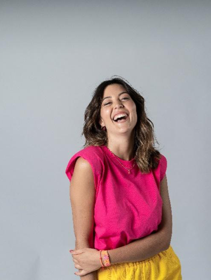 Dona rient amb expressió alegre, braços plegats i fons neutre.